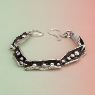 A sterling silver bracelet with handmade volcano-inspired design, featuring silver balls and grips linked together with a silver hook clasp.
