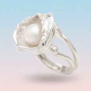 Silver ring with a pearl on a light blue background