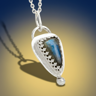Silver pendant with blue stone on a white background