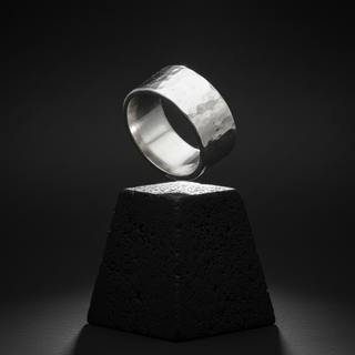 A silver ring on a clear, solid surface, with a textured surface and a bright, shiny finish.